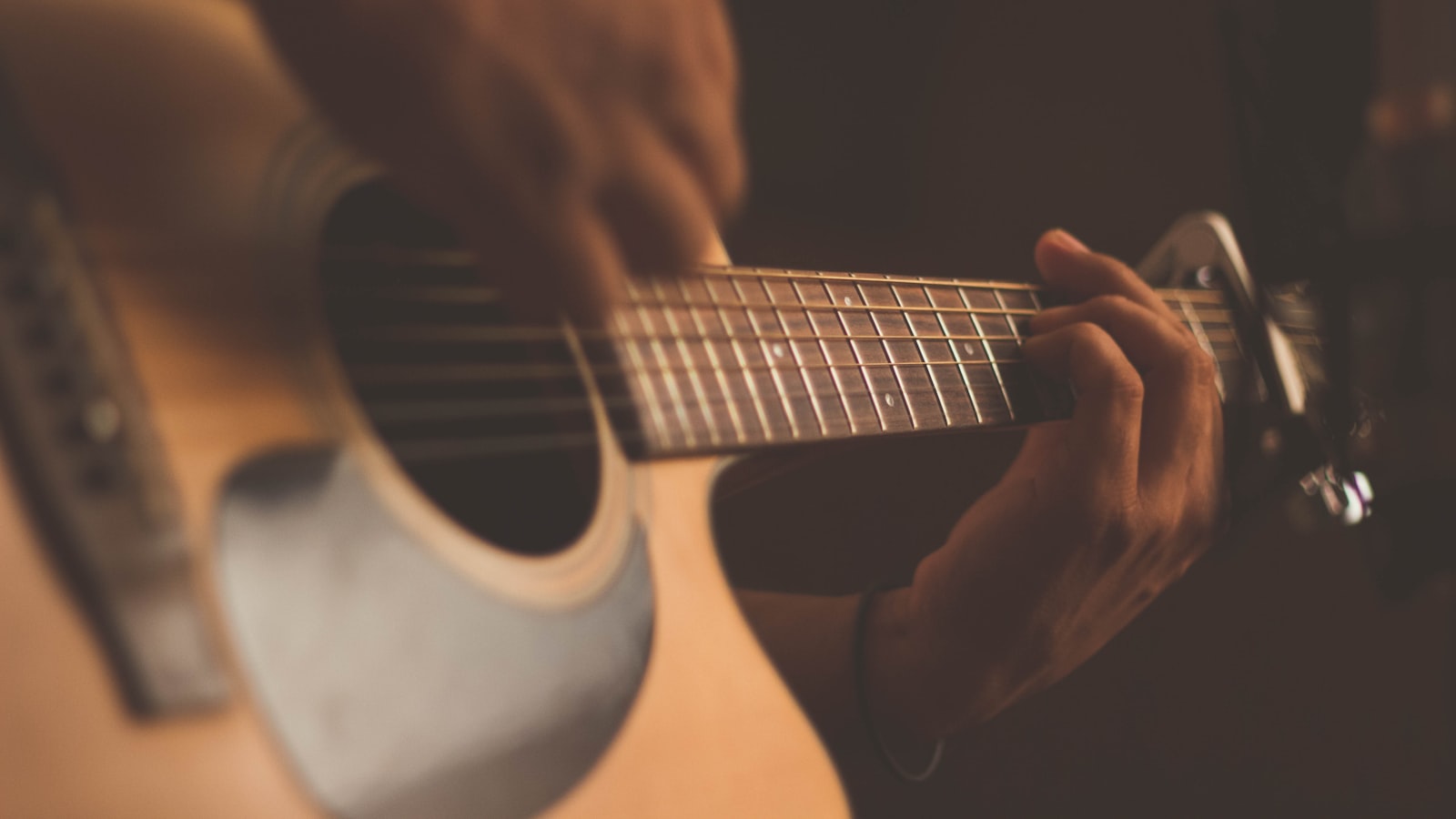 A person holding an acoustic guitar near an open window with morning light
